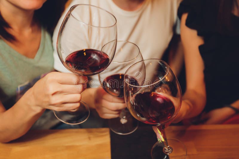 Close up shot of group of people clinking glasses with wine or champagne in front of bokeh background. older people