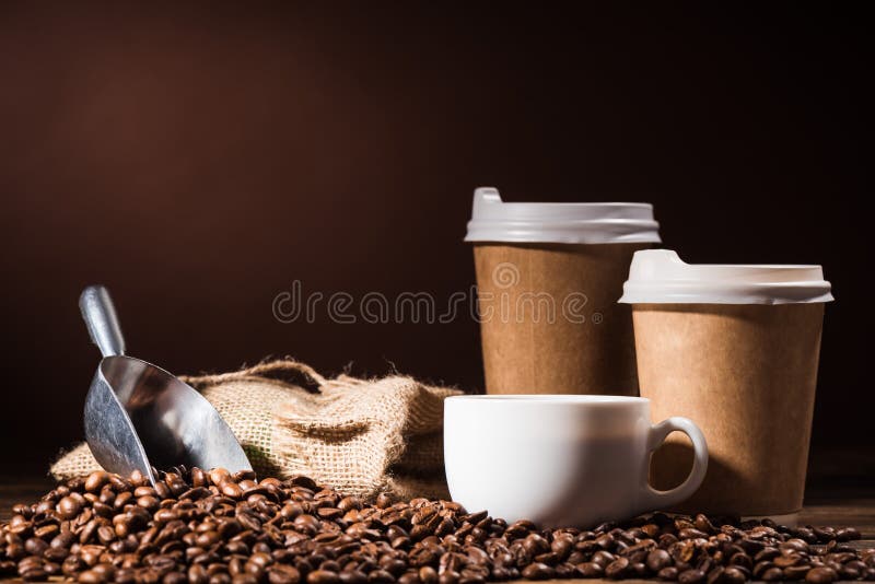 close-up shot heap of coffee beans with paper cups, scoop and mug on rustic