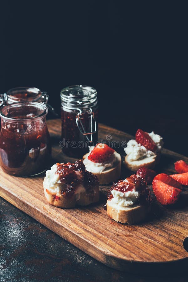 close up shot of jars with jam, sandwiches with cream cheese, strawberry slices and fruit jam on cutting board royalty free stock photo close up shot of jars with jam, sandwiches with cream cheese, strawberry slices and fruit jam on cutting board royalty free stock photo