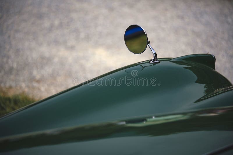 Close up shot of a round rear view mirror on a vintage car