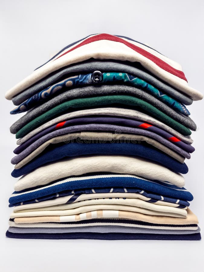 Stack of neatly folded shirts in various colors and patterns on white background stock image