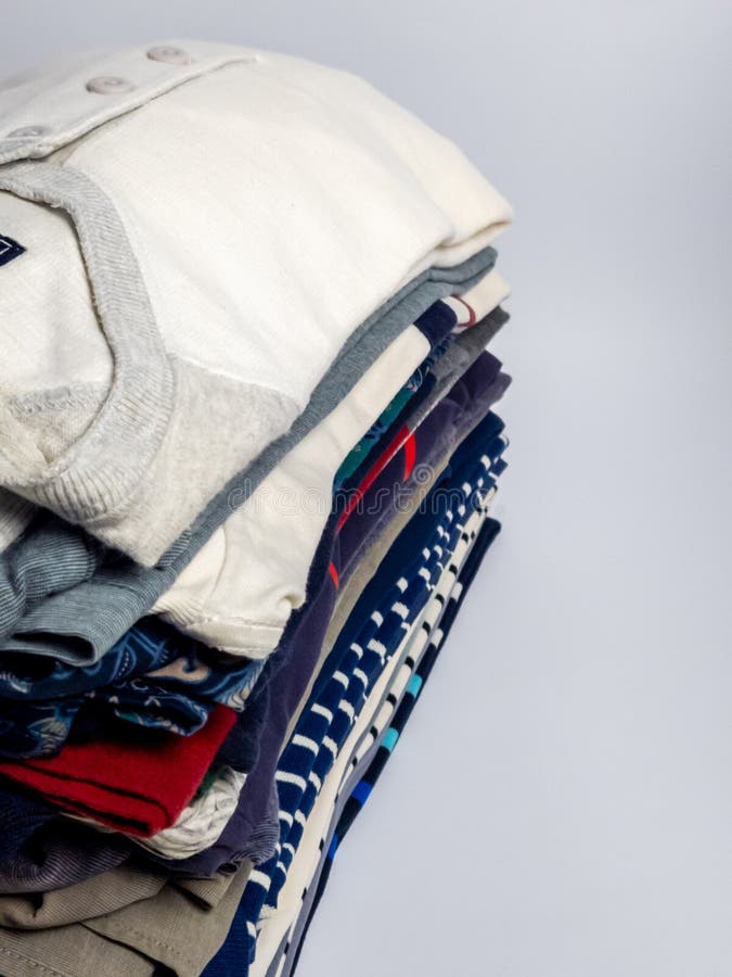Stack of neatly folded clothing on a plain background with copy space stock image