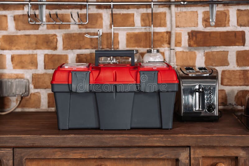 Close-up shot of toolbox standing on kitchen table with toaster in front of