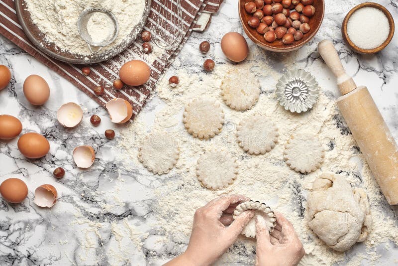 Close-up shot. Top view of a baker cook place, hands are working with a raw dough on the marble table background.