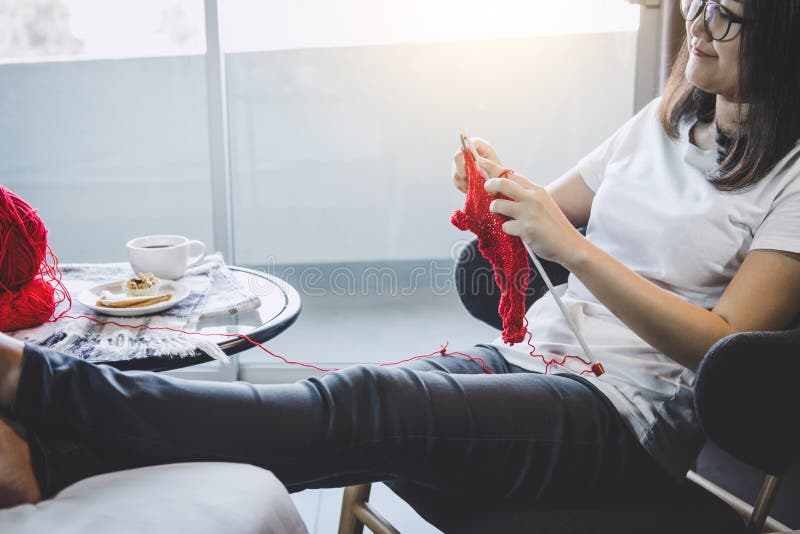 Close up shot of young woman hands knitting a red scarf handicraft in the living room on terrace at home royalty free stock photography Close up shot of young woman hands knitting a red scarf handicraft in the living room on terrace at home royalty free stock photography