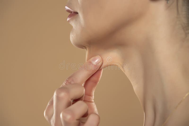 A close-up and side profile view of a caucasian lady pinching the loose skin at the front of her throat. Commonly called a turkey