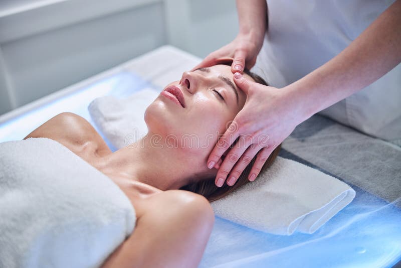 Pretty Caucasian Female Lying On Massage Table While Enjoying Spa Procedure In Spa Center Stock