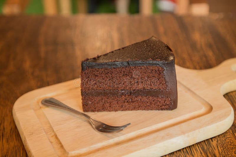 Close up Slice of chocolate cake with frok on wood table.