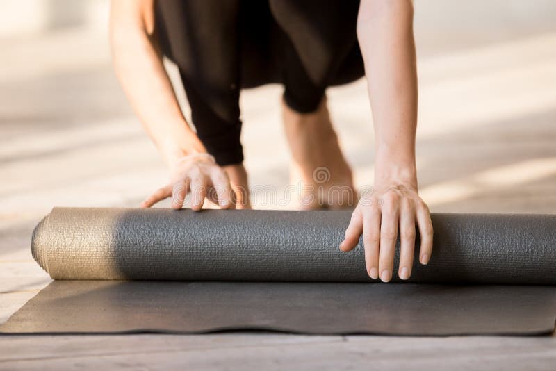 Closeup Of Athletic Woman Rolling Up Her Exercise Mat After