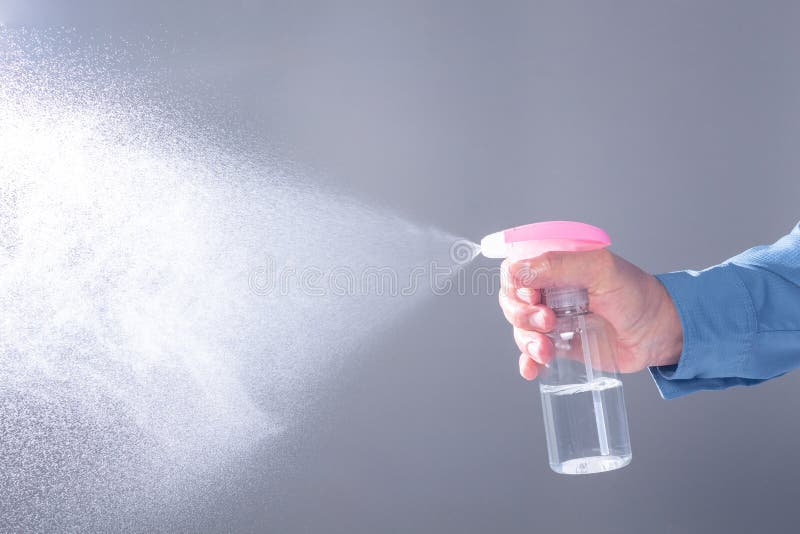 Close-up of a spray making splash of alcohol gel or water on a gray background