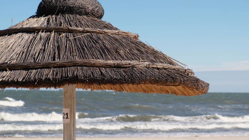 Close up of Straw beach rattan parasol at the empty beach with blue sky backgrounds sea ocean coast. Relaxing day