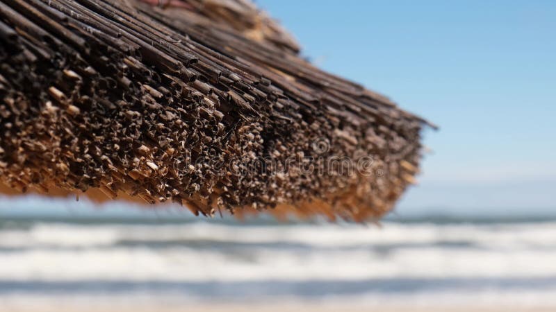 Close up of Straw beach rattan parasol at the empty beach with blue sky backgrounds sea ocean coast. Relaxing day