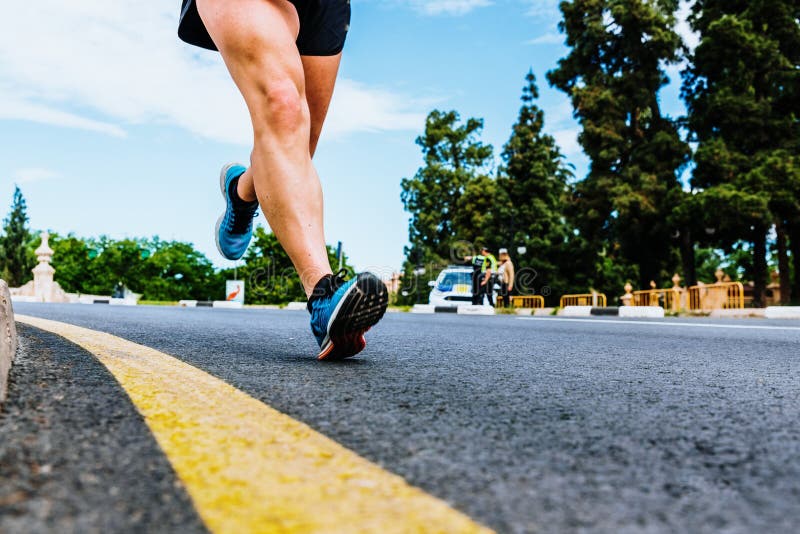 Close-up of the stride of an expert runner against the asphalt ground from the heel, cause of sports injury, during a race.