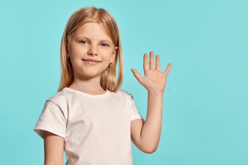Close-up studio shot of a lovely blonde little girl in a white t-shirt posing against a blue background. royalty free stock photos Close-up studio shot of a lovely blonde little girl in a white t-shirt posing against a blue background. royalty free stock photos