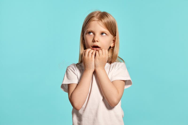 Close-up studio shot of a lovely blonde little girl in a white t-shirt posing against a blue background. royalty free stock photos Close-up studio shot of a lovely blonde little girl in a white t-shirt posing against a blue background. royalty free stock photos