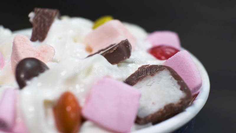 Close-up sweet dessert with cream and marshmallows on a rotating table on black background. stock footage