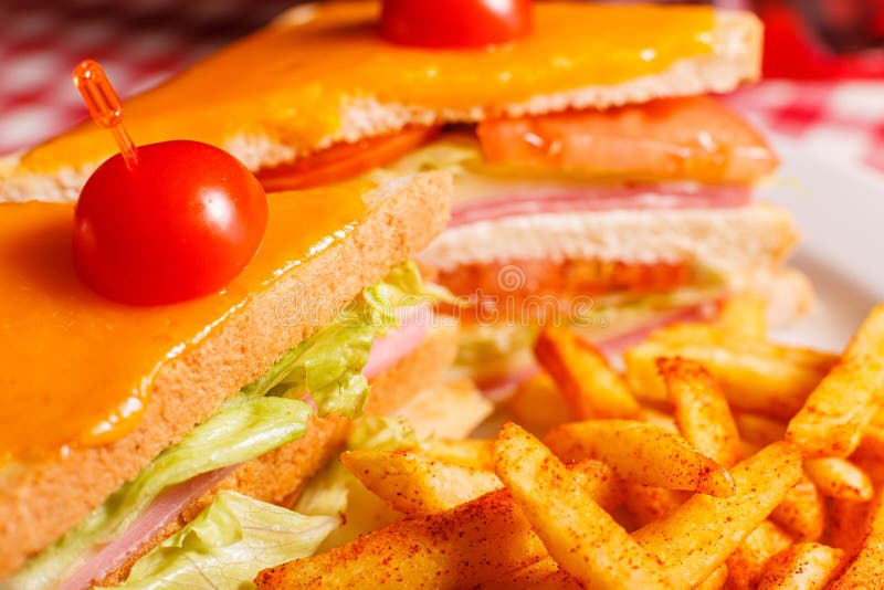 Close up Tasty grilled sandwich in the restaurant. Club sandwich with ham, tomato, cheese and lettuce. Served with royalty free stock image Close up Tasty grilled sandwich in the restaurant. Club sandwich with ham, tomato, cheese and lettuce. Served with royalty free stock image