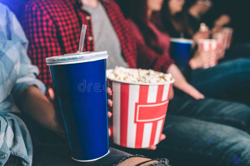 Close up of tasty but unhealthy food. There are basket of popcorn and a blue cup of coke on picture. Man and woman are stock photos Close up of tasty but unhealthy food. There are basket of popcorn and a blue cup of coke on picture. Man and woman are stock photos