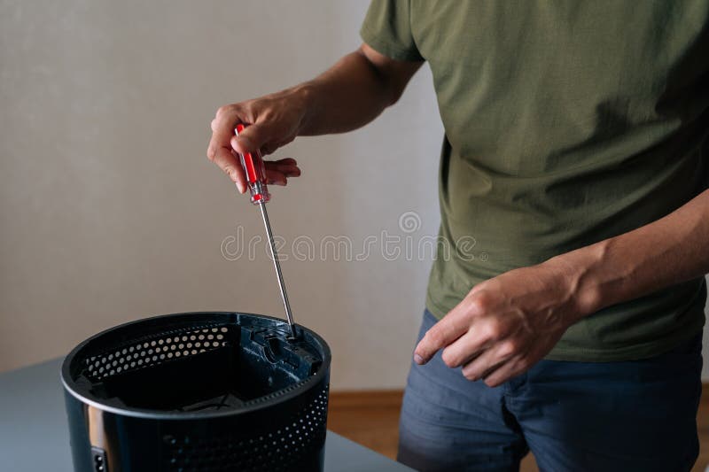 Close-up of technician hand using screwdriver to repair or maintain air humidifier, emphasizing importance of regular stock photos