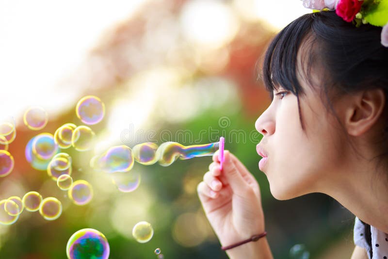 Close up teenager girl blowing soap bubbles