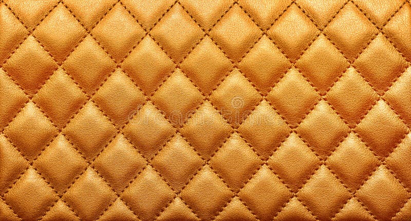 Close-up texture of genuine leather with rhombic stitching. Rich gold color