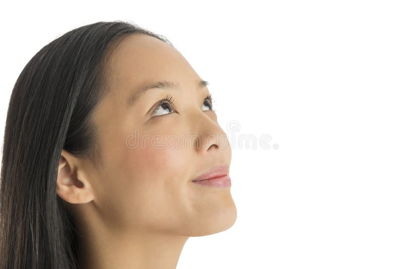 Close-up of thoughtful mid adult woman smiling while looking up against white background. Close-up of thoughtful mid adult woman smiling while looking up against white background