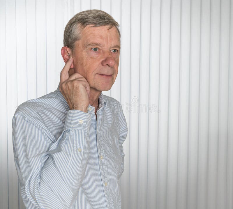 Close up of a tiny modern hearing aid with senior man
