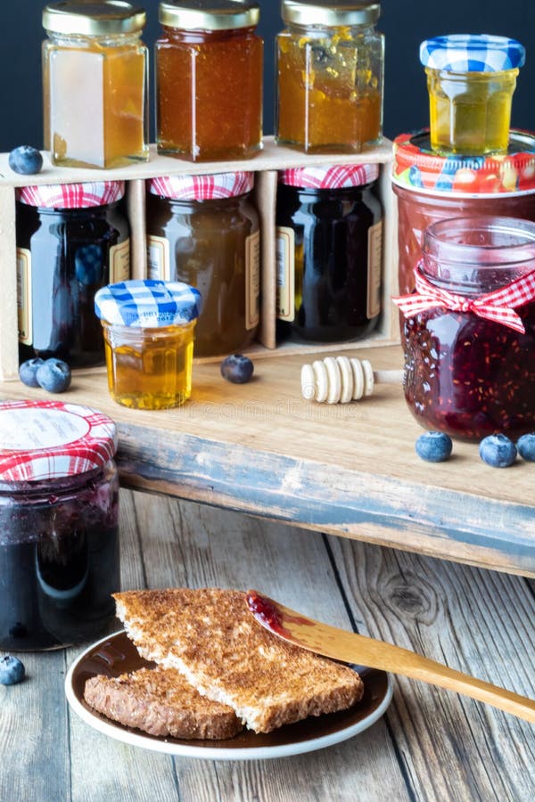 A close up of toast and raspberry jam with jars of jam and honey in crisp focus in behind. Various sweet preserves stock images, royalty-free photos and pictures