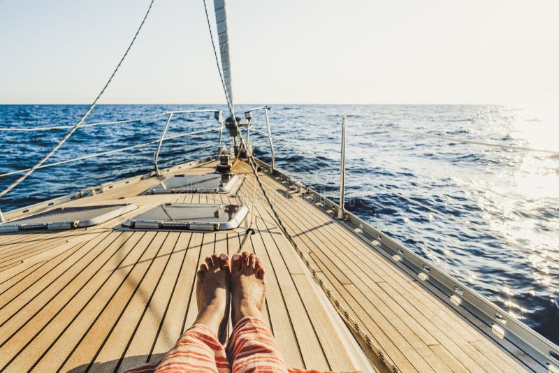 Close up of tourist woman caucasian feet lay down and relaxing enjoying a sail boat trip with ocean around and horizon in