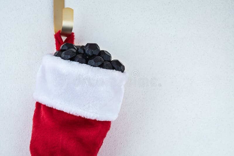 Close up of traditional red and white plush Christmas stocking stuffed with coal shaped candy