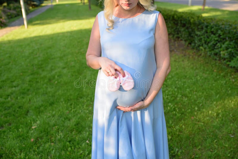 Close Up Of The Tummy Of A Pregnant Girl In A Blue Dress On A Warm Sunny Day In Nature Stock 