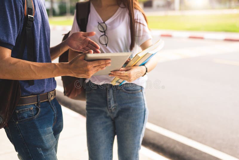 Close Up Of Two College Student Discussion With Tablet. Girl Holding Books Talking To Boy In University Or School. Education And