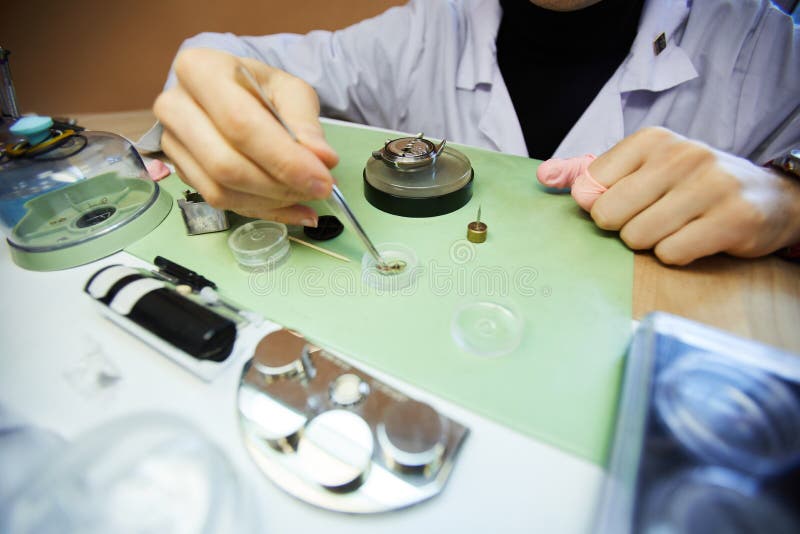 Using tweezer for assembling wristwatch. Close-up of unrecognizable laboratory engineer using tweezer to take small cogs while assembling wristwatch