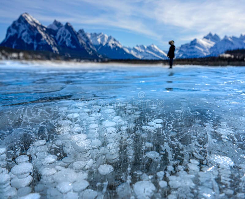 CLOSE UP: Unrecognizable person stands on frozen Lake Abraham full of bubbles