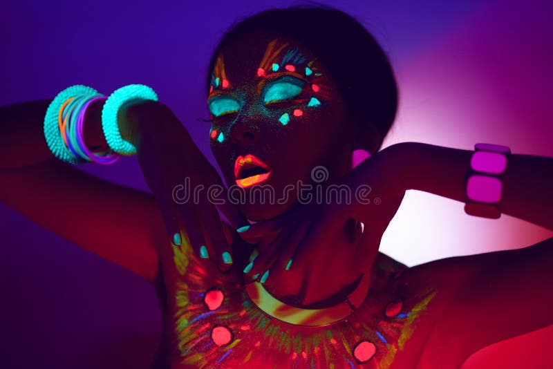 Close up UV profile portrait of a sensual young woman with artistic colorful makeup, isolated violet orange background.