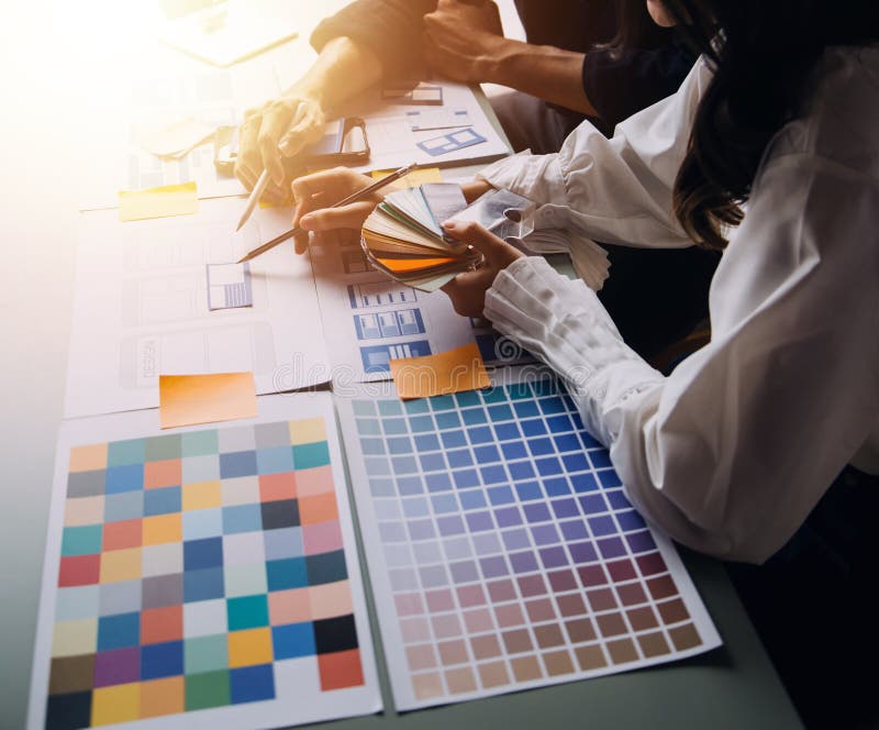 Close up ux developer and ui designer brainstorming about mobile app interface wireframe design on table with customer breif and stock photography