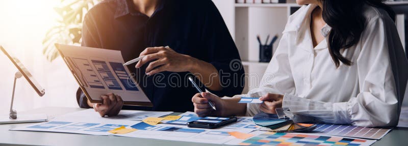 Close up ux developer and ui designer brainstorming about mobile app interface wireframe design on table with customer breif and royalty free stock image