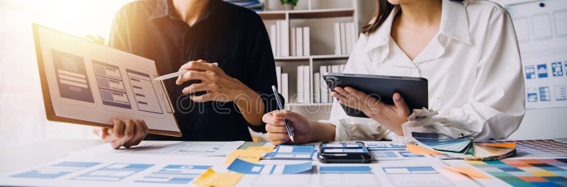 Close up ux developer and ui designer brainstorming about mobile app interface wireframe design on table with customer breif and royalty free stock images