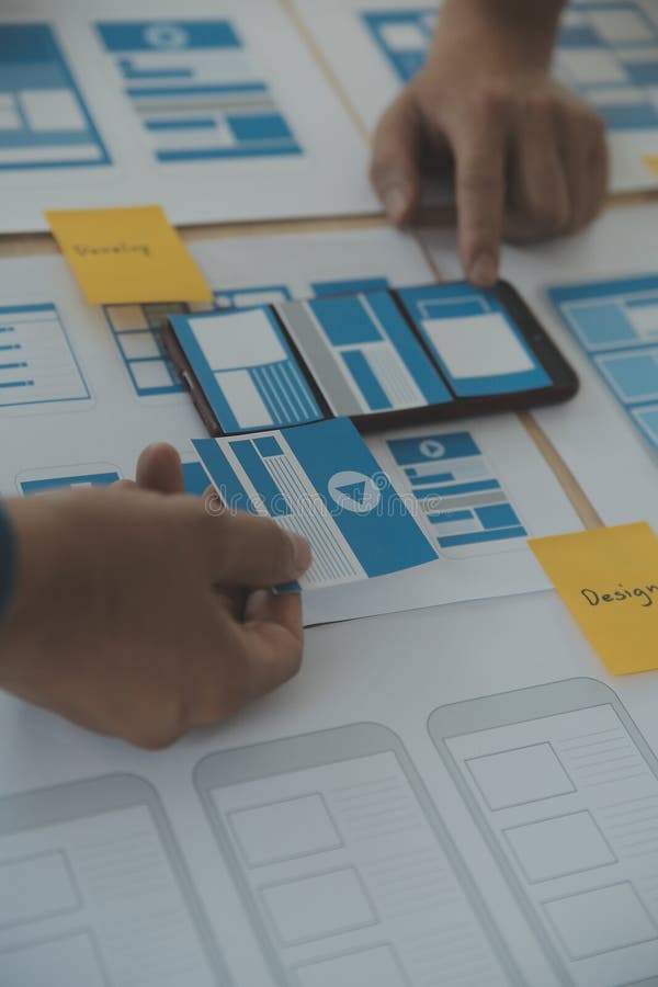 Close up ux developer and ui designer brainstorming about mobile app interface wireframe design on table with customer breif and royalty free stock photography