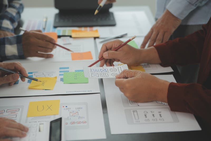 Close up ux developer and ui designer brainstorming about mobile app interface wireframe design on table with customer breif and royalty free stock photos