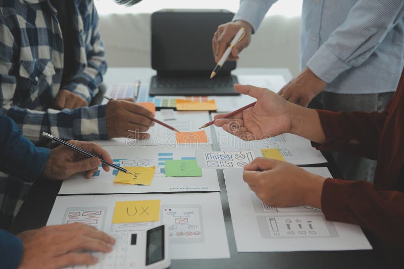 Close up ux developer and ui designer brainstorming about mobile app interface wireframe design on table with customer breif and royalty free stock images