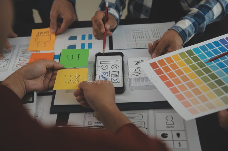 Close up ux developer and ui designer brainstorming about mobile app interface wireframe design on table with customer breif and royalty free stock photography