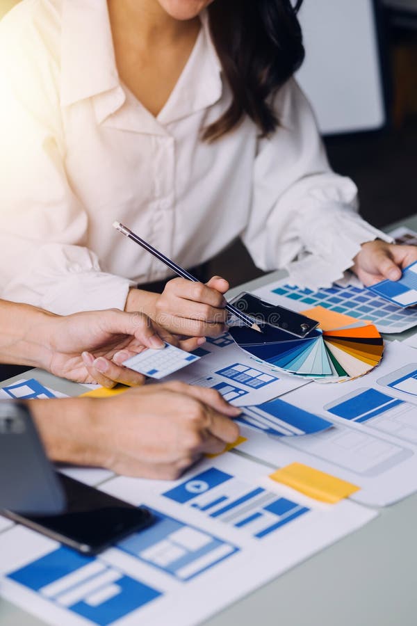 Close up ux developer and ui designer brainstorming about mobile app interface wireframe design on table with customer breif and stock photography