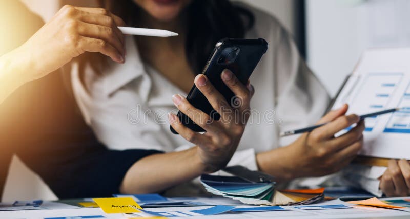 Close up ux developer and ui designer brainstorming about mobile app interface wireframe design on table with customer breif and stock image