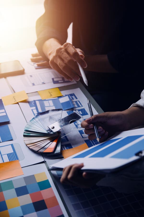 Close up ux developer and ui designer brainstorming about mobile app interface wireframe design on table with customer breif and stock photography