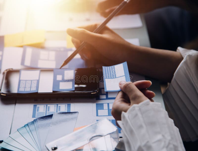 Close up ux developer and ui designer brainstorming about mobile app interface wireframe design on table with customer breif and royalty free stock image