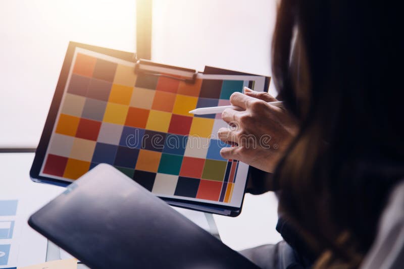 Close up ux developer and ui designer brainstorming about mobile app interface wireframe design on table with customer breif and stock images
