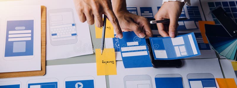 Close up ux developer and ui designer brainstorming about mobile app interface wireframe design on table with customer breif and royalty free stock photos