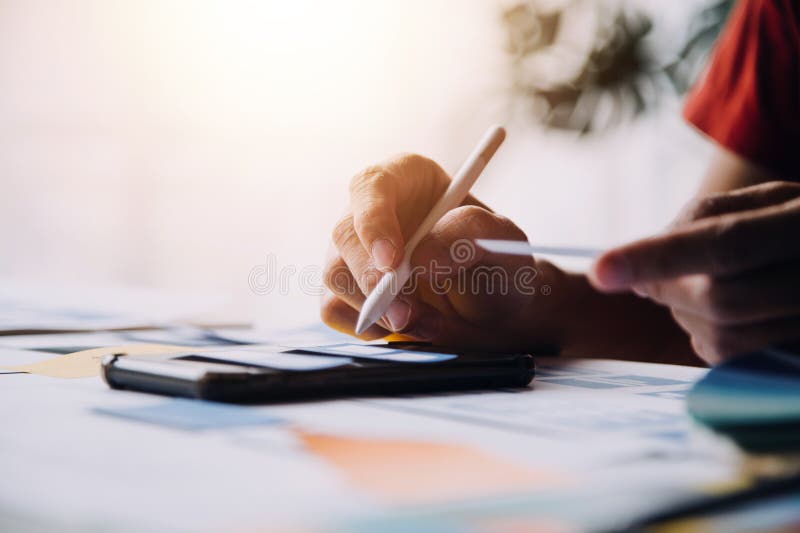 Close up ux developer and ui designer brainstorming about mobile app interface wireframe design on table with customer breif and stock photos