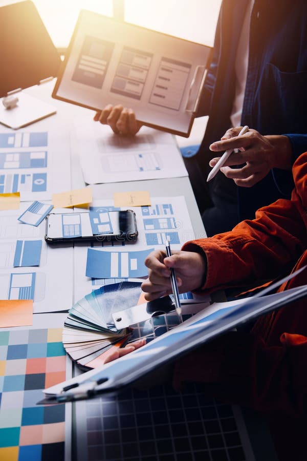 Close up ux developer and ui designer brainstorming about mobile app interface wireframe design on table with customer breif and royalty free stock photo